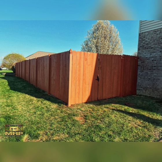 A wooden fence is sitting in the middle of a lush green field.