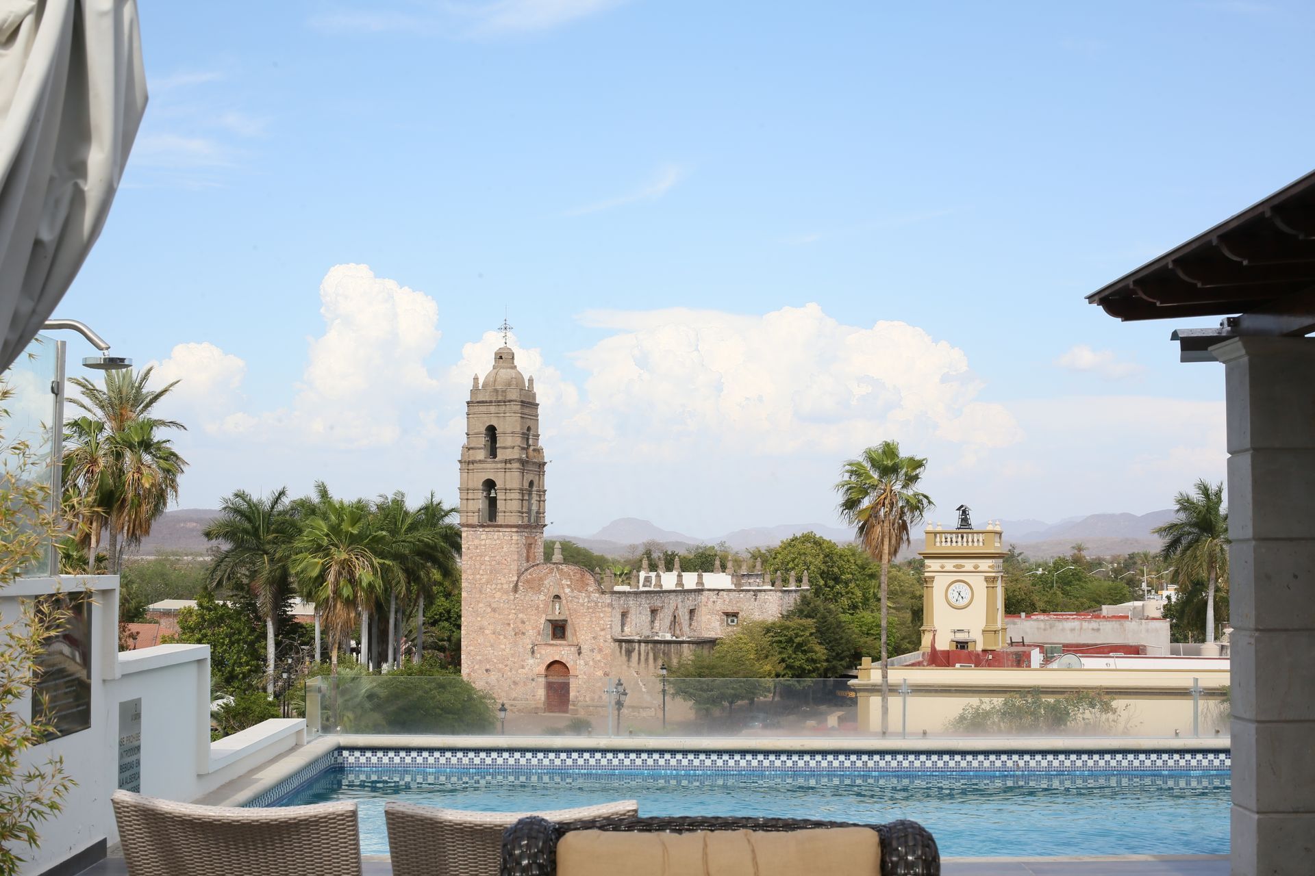A view of a city from a rooftop pool with a clock tower in the background