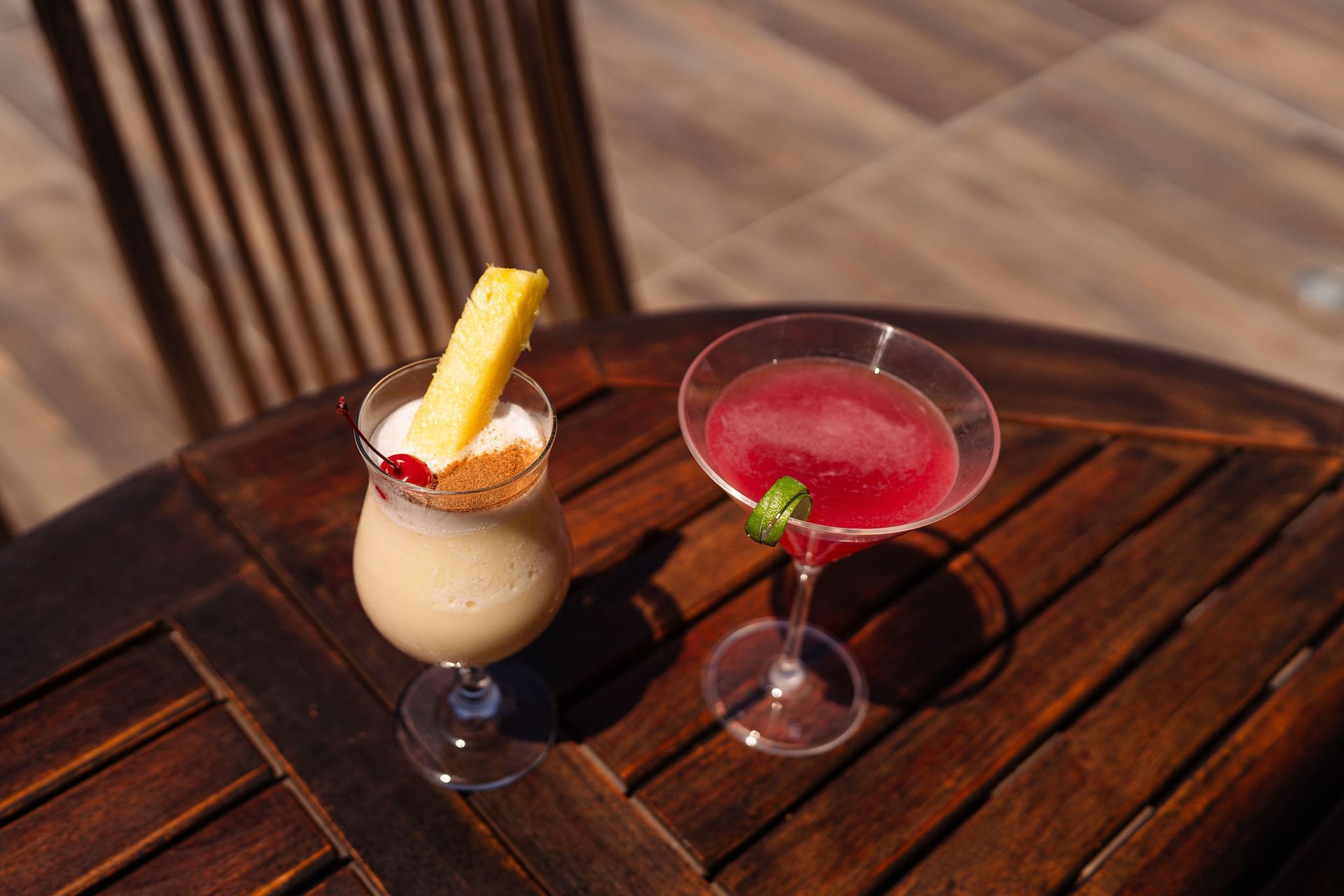 Two cocktails are sitting on a wooden table.