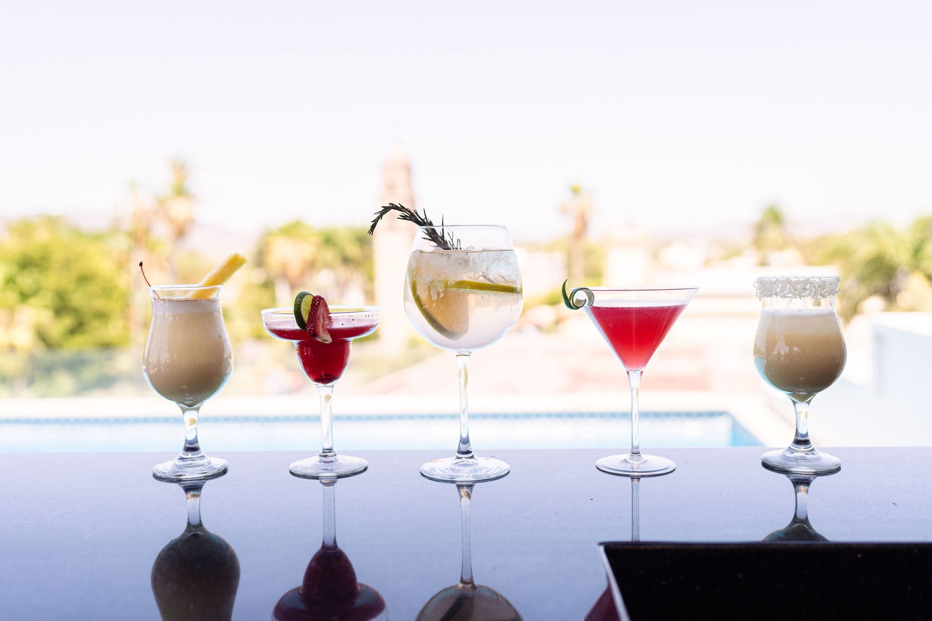 Four different types of cocktails are sitting on a bar.