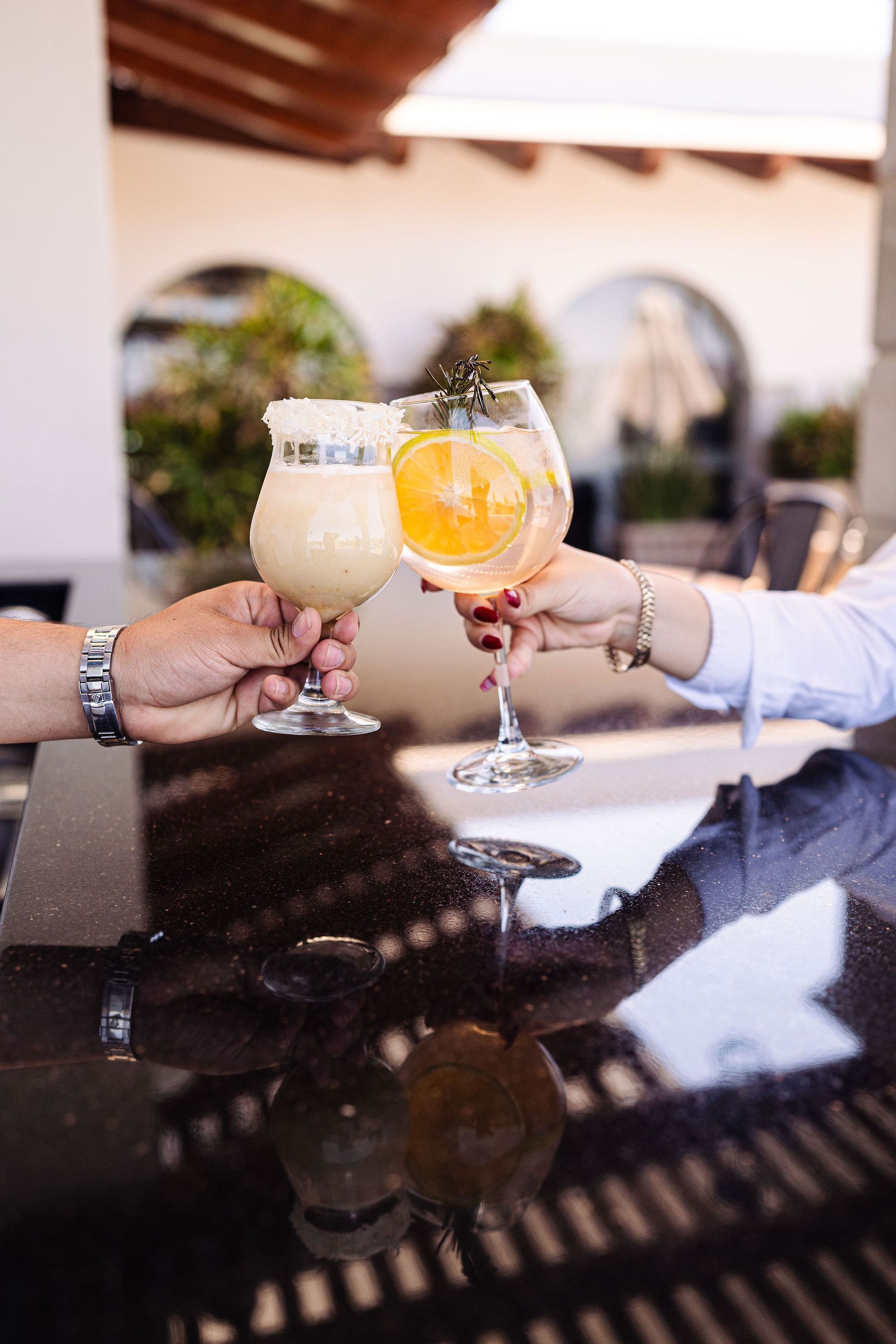 A man and a woman are toasting with drinks at a bar.