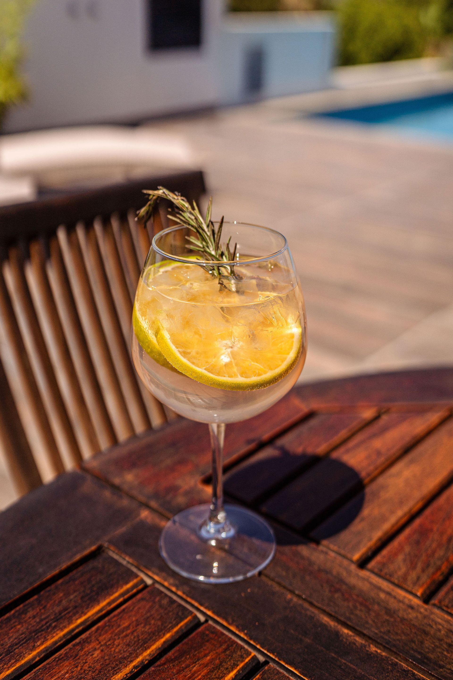 A glass of gin and tonic with a slice of lemon on a wooden table.