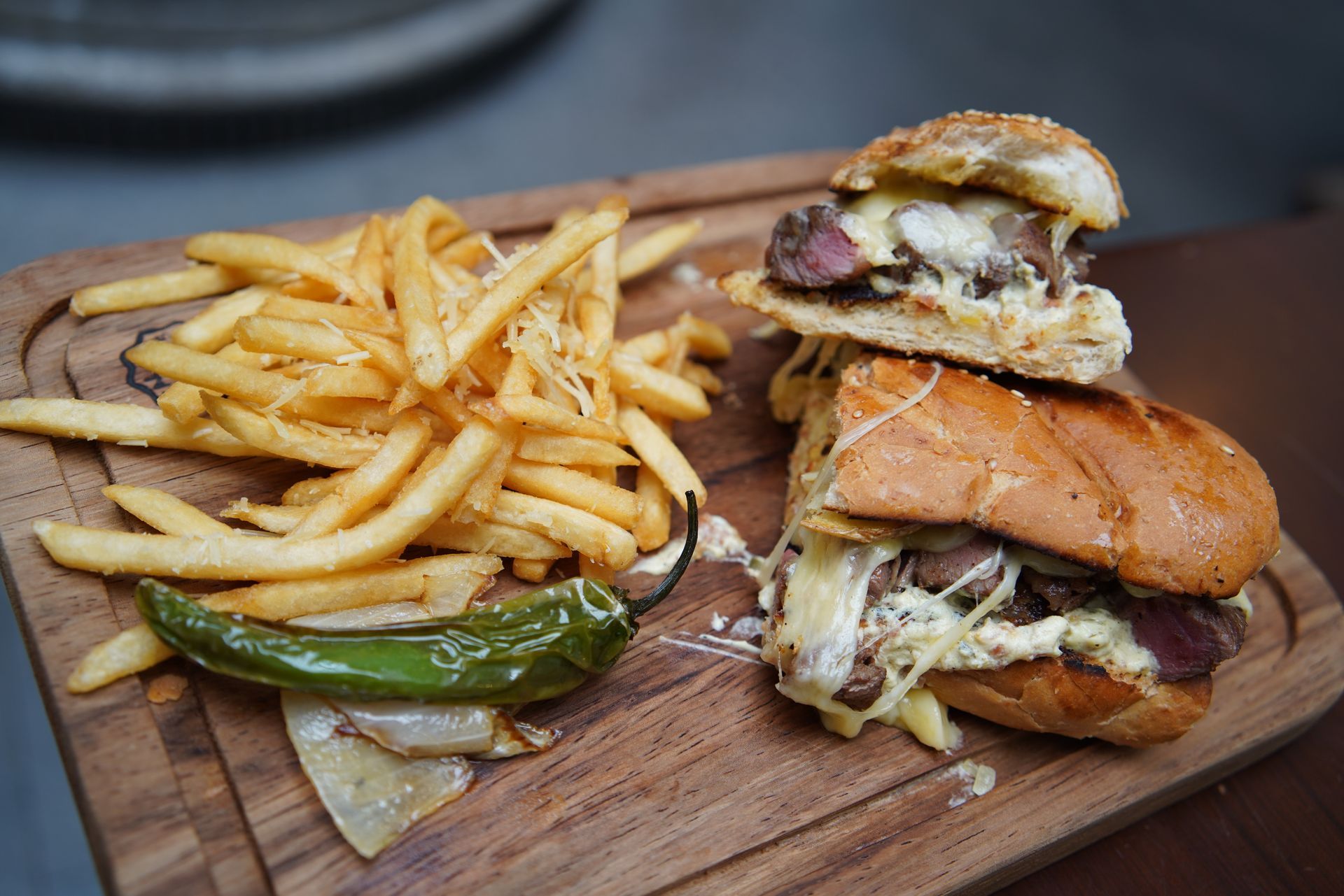 A sandwich and french fries on a wooden cutting board.