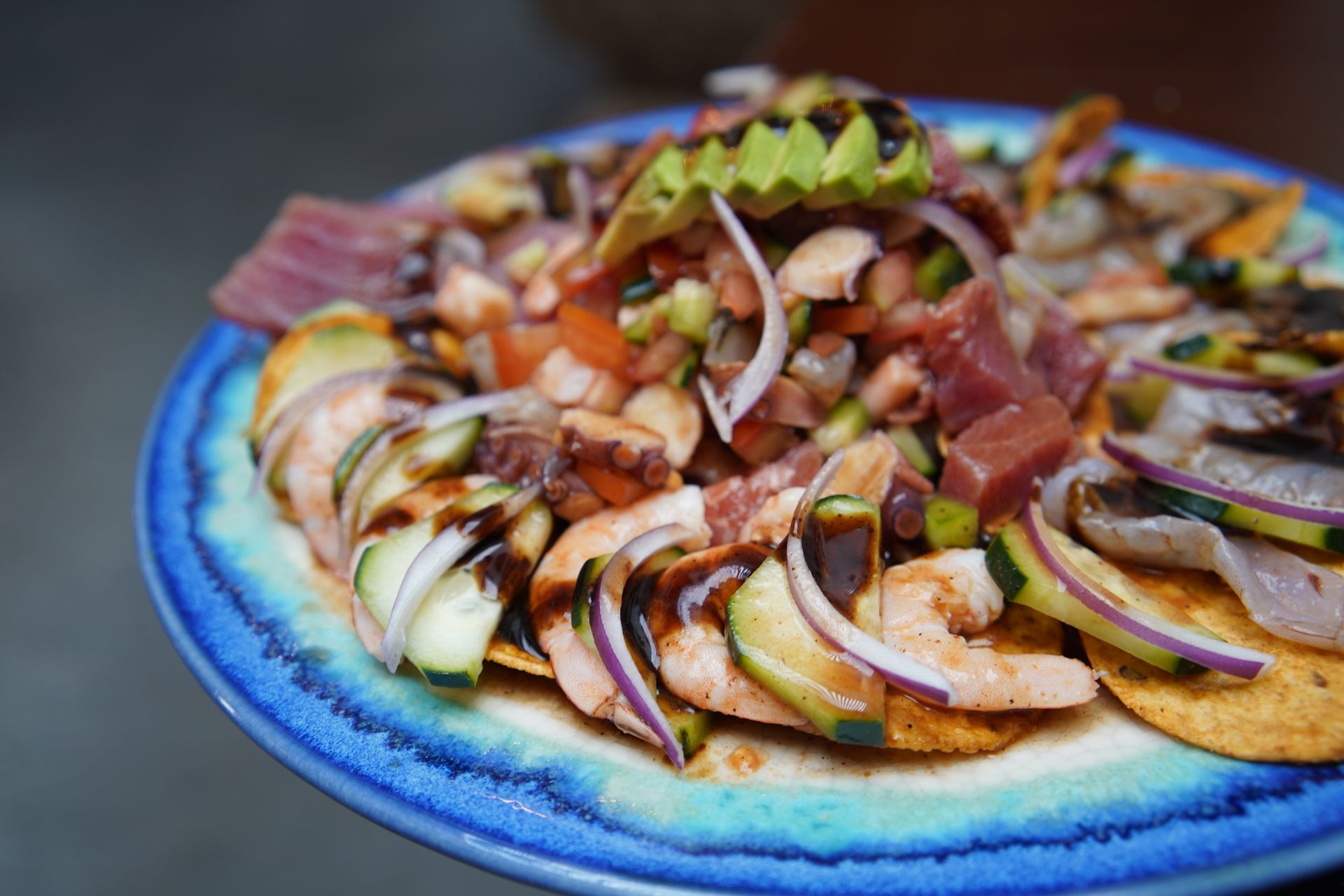 A blue plate topped with a salad of shrimp , onions , and avocado.
