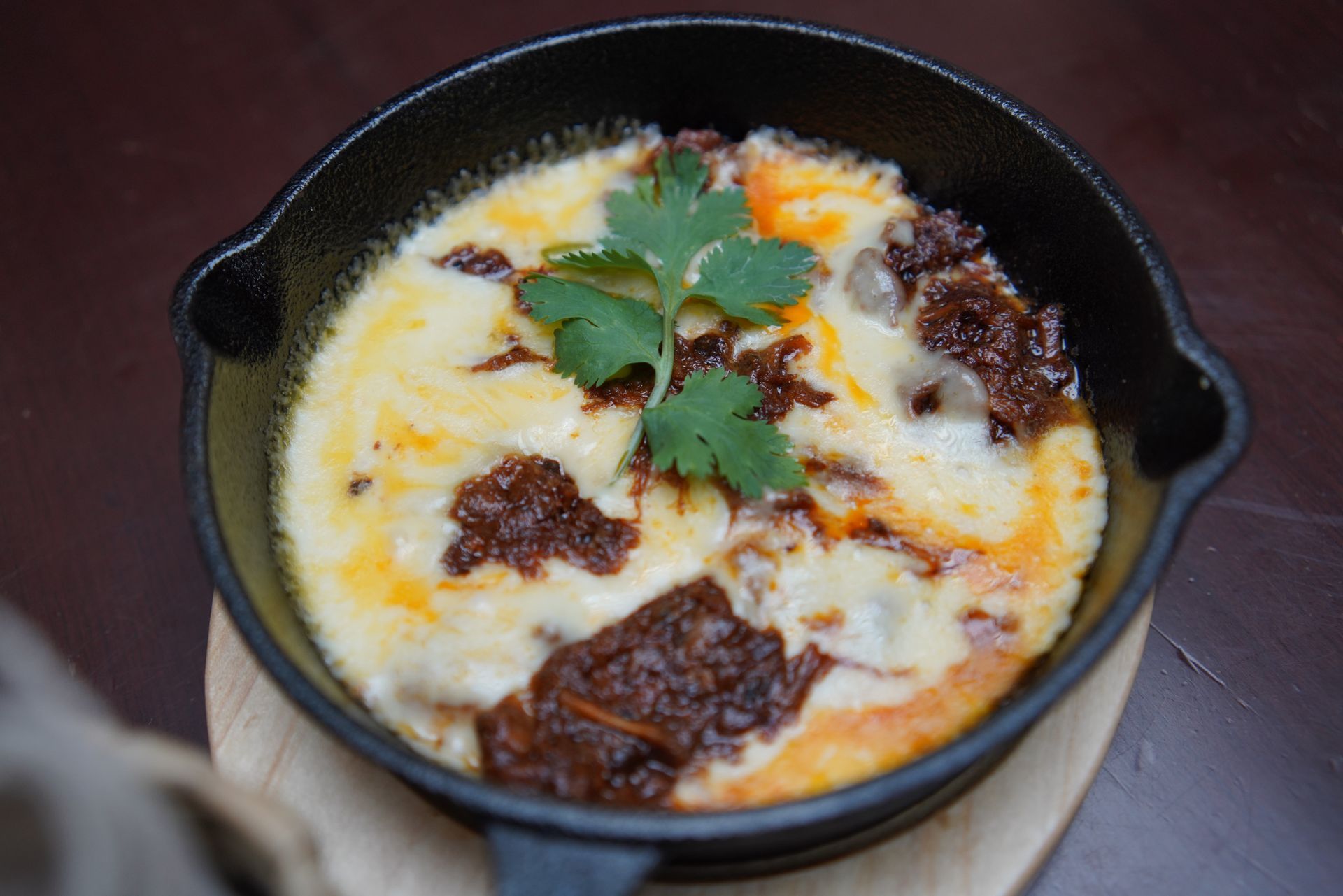 A skillet filled with food is sitting on a wooden table.