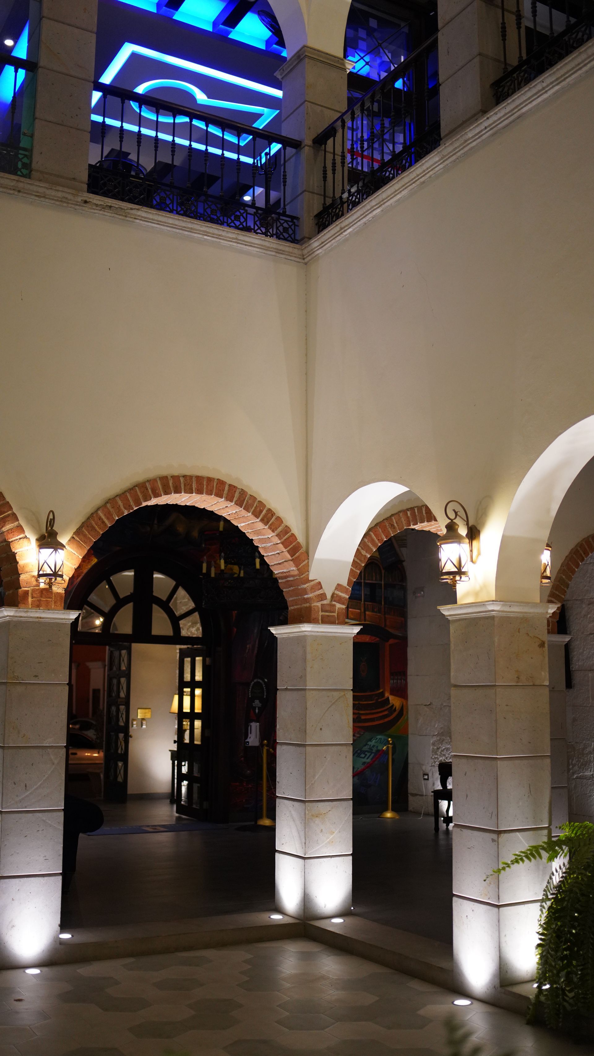 A building with arches and columns is lit up at night.