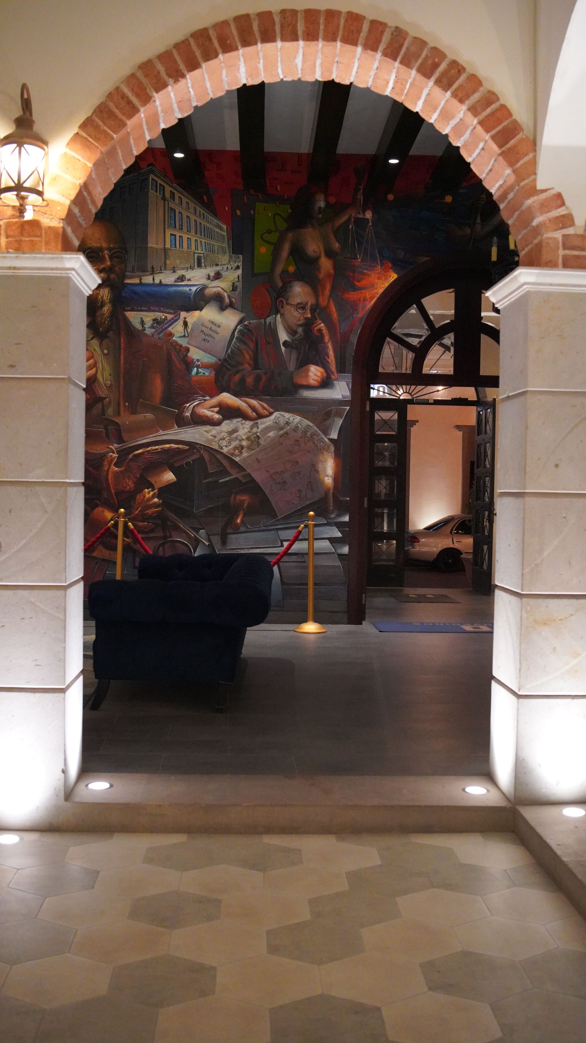 A room with a painting on the wall and a brick archway