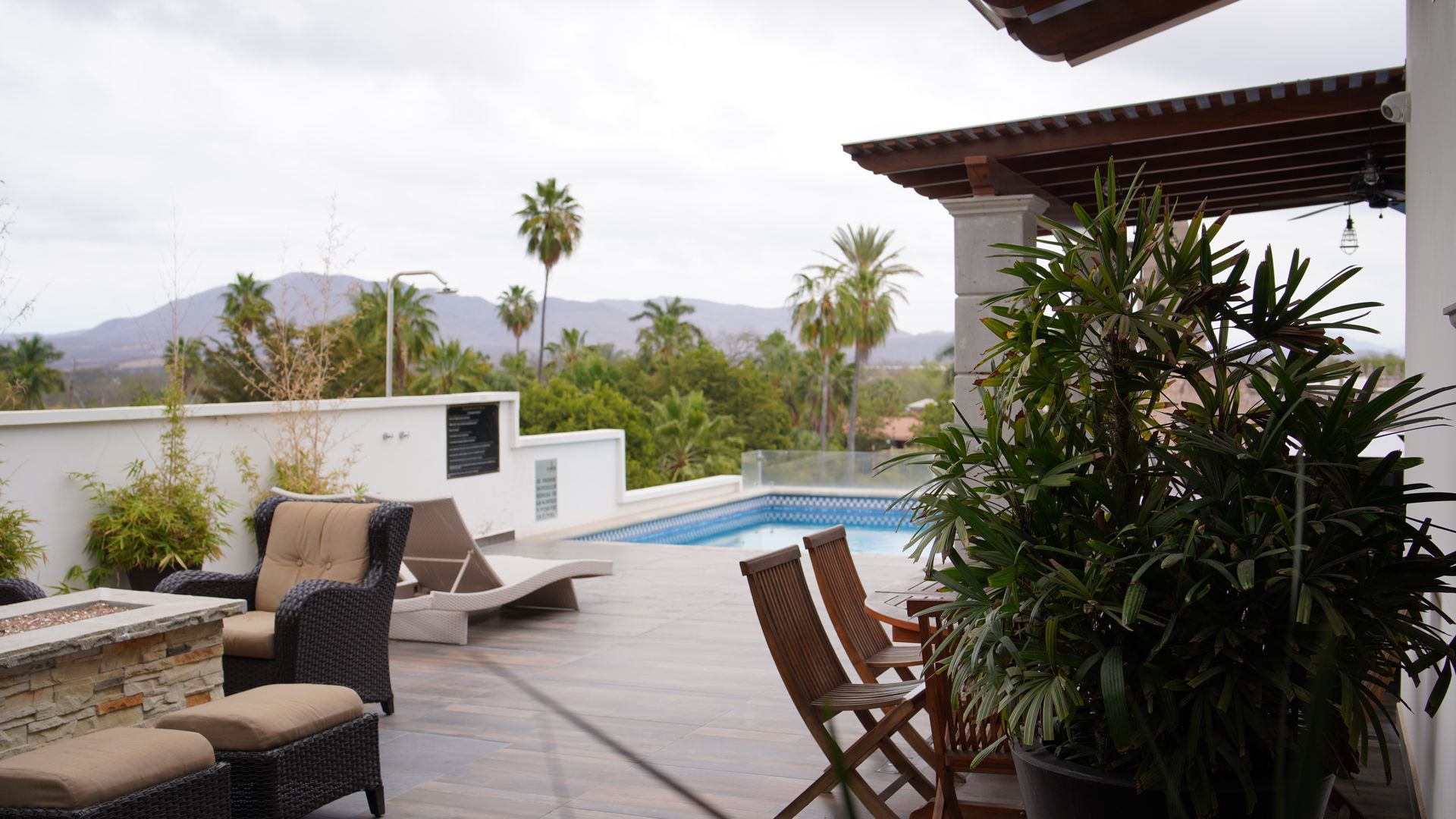A patio with chairs and a swimming pool with mountains in the background