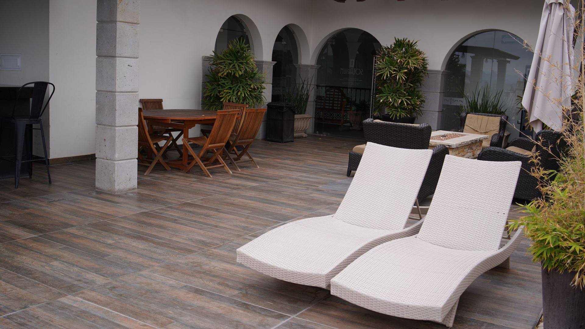 Two white lounge chairs are sitting on a wooden deck next to a table and chairs.