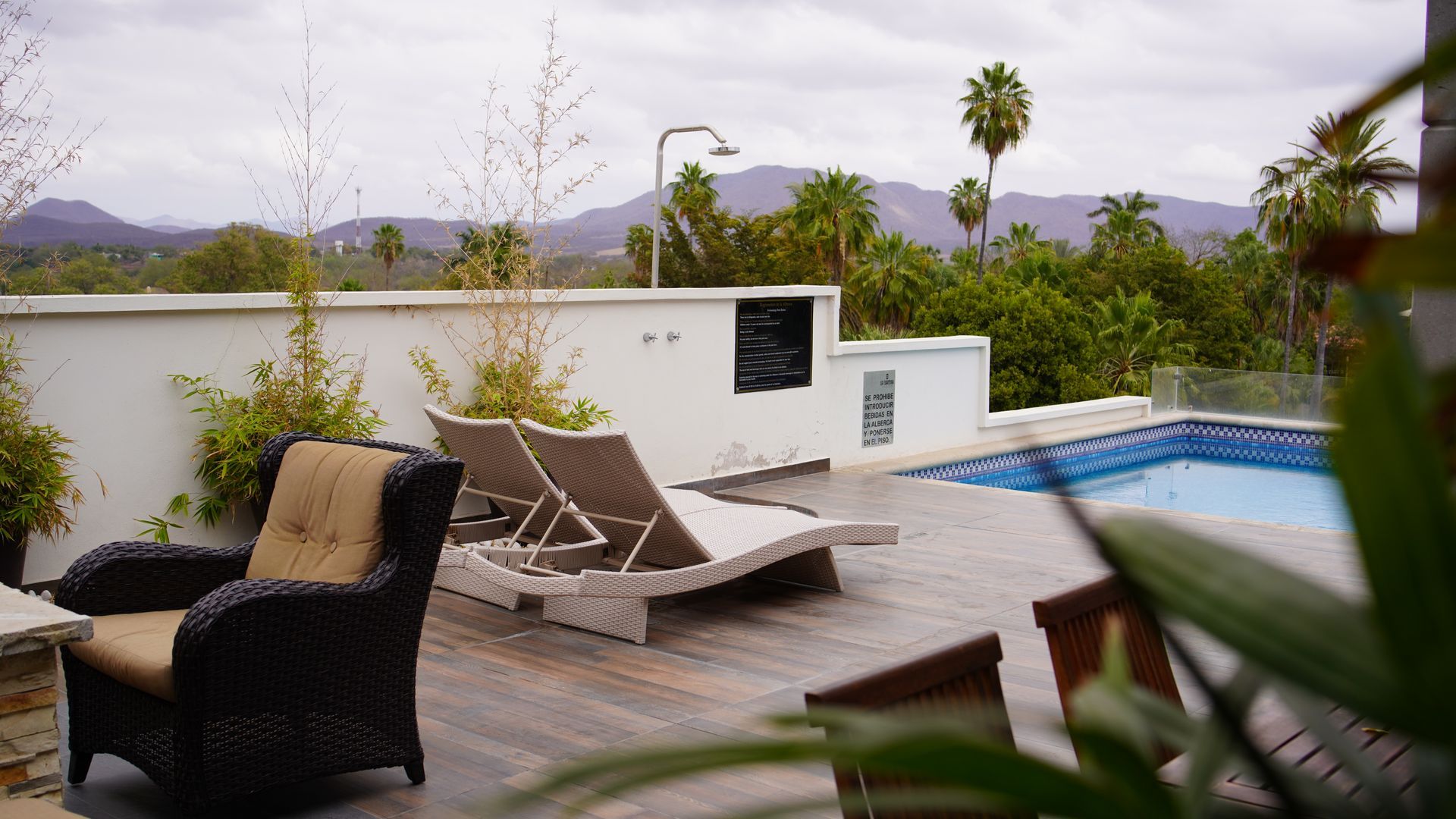 A patio with chairs and a swimming pool in the background