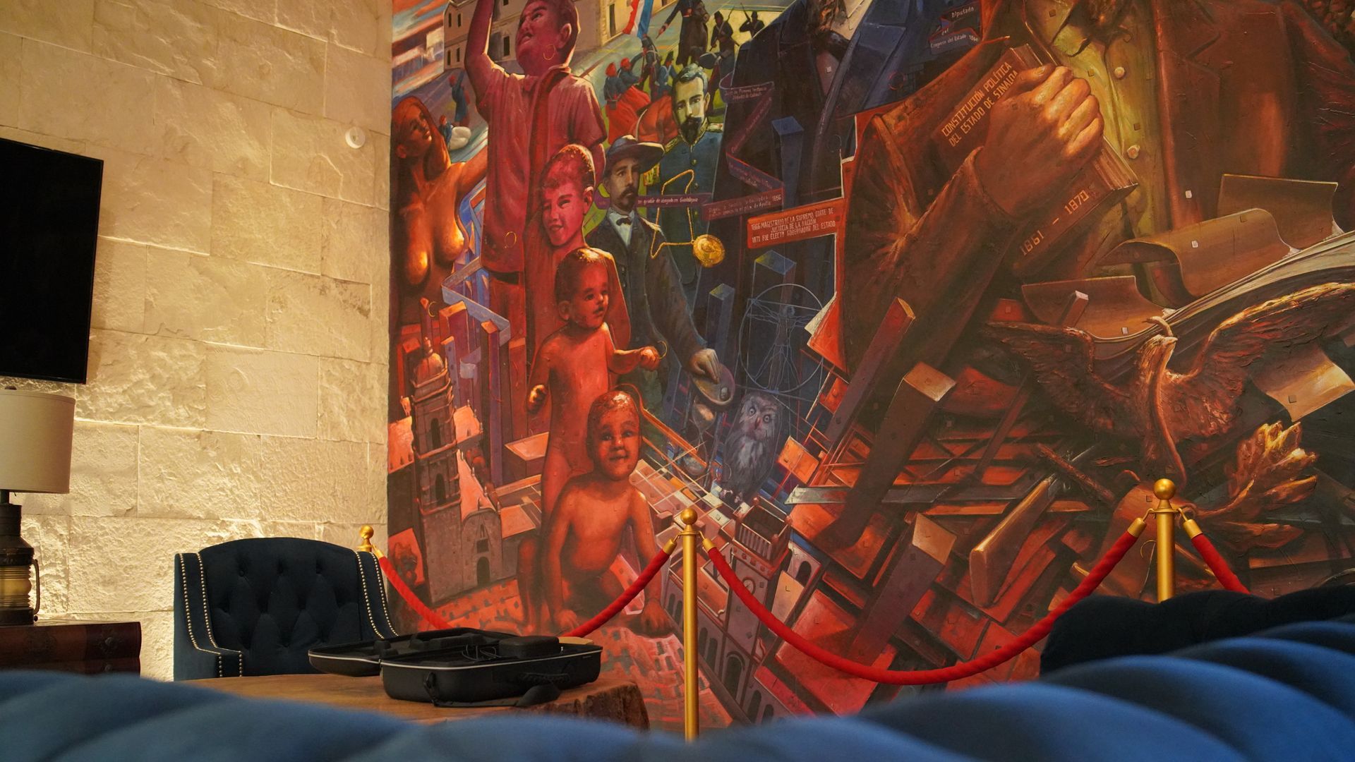 A room with a large painting on the wall and a couch.