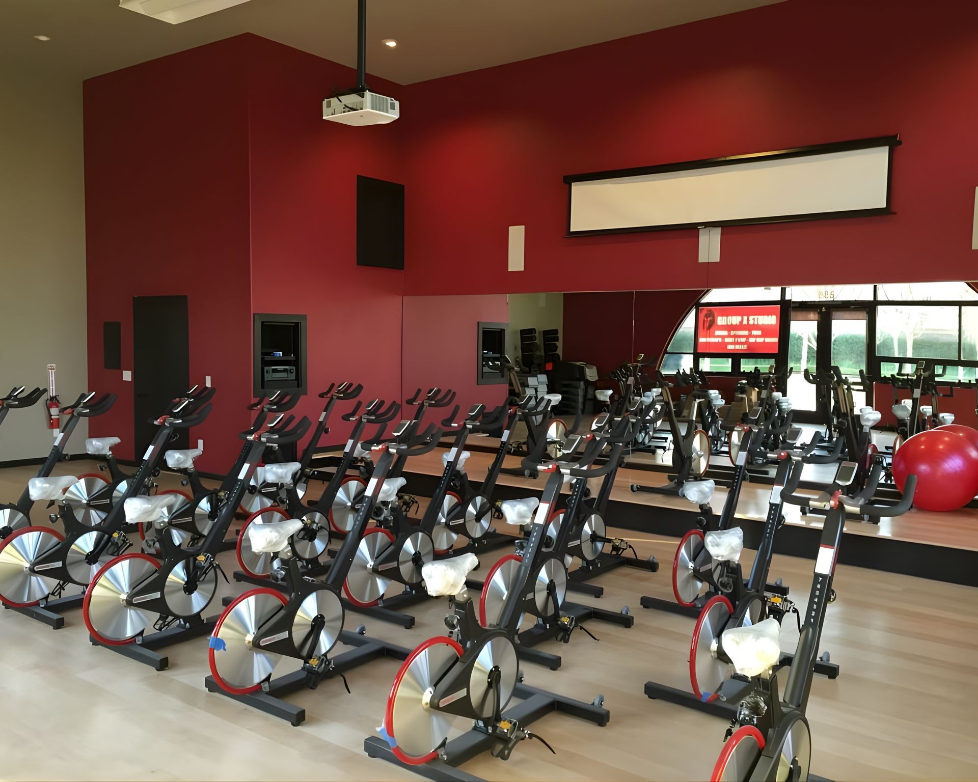 A row of exercise bikes are lined up in a gym.