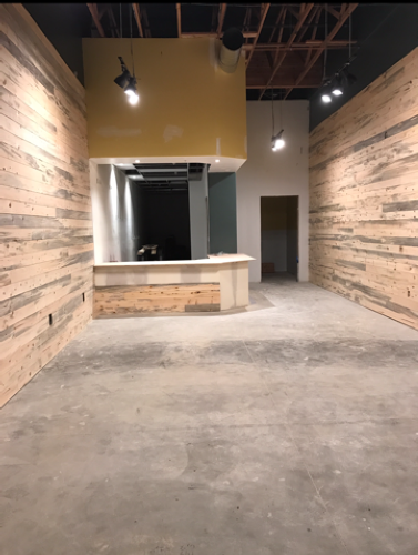 A man is working on a wooden counter in a room