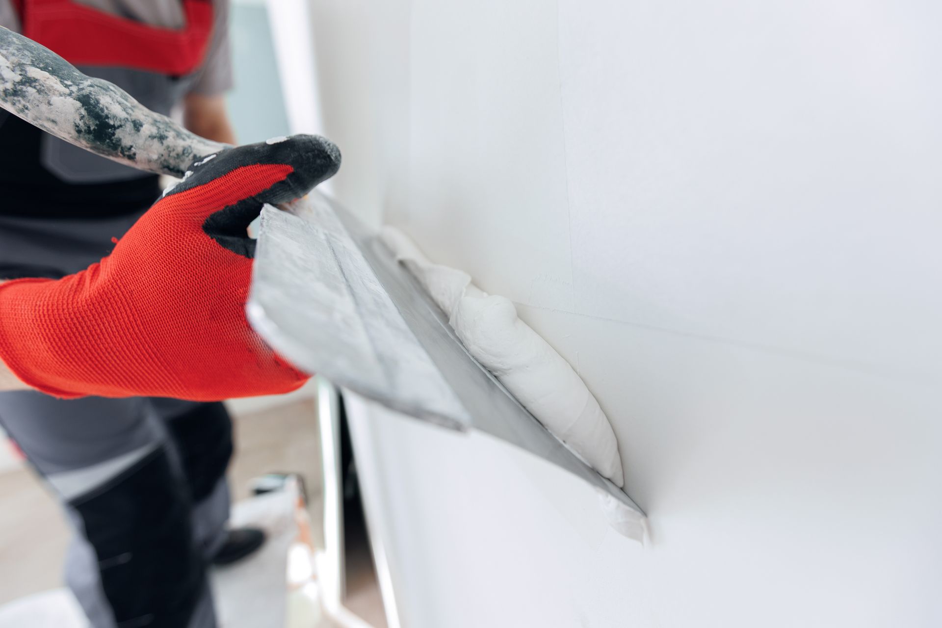 A person is plastering a wall with a trowel.