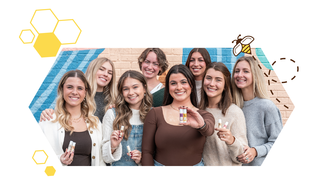 Group of smiling women holding Honey Helps lip balm, showing community support and honey-inspired products