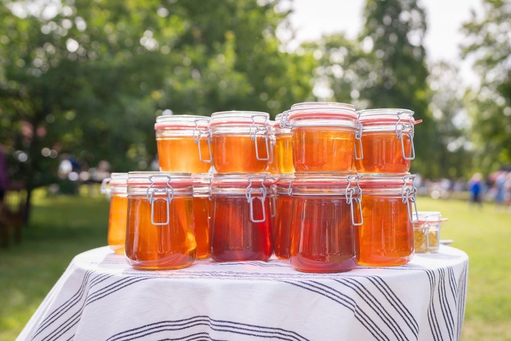 Jars of honey on a table outdoors; a display for sale.