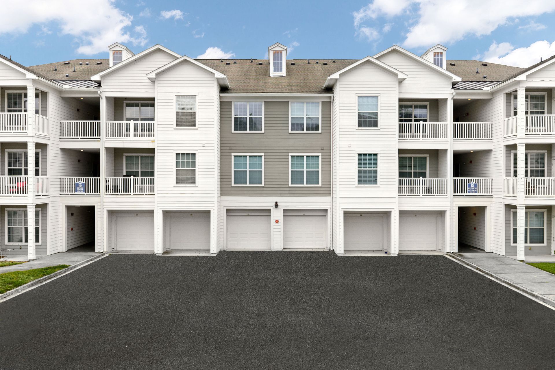 Apartment complex with white buildings reflected in a calm lake under a blue sky.