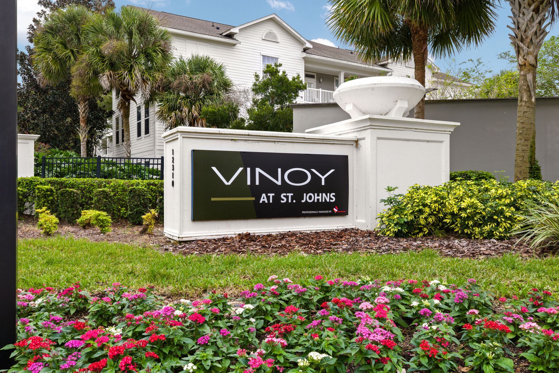 Outdoor patio with wicker furniture, white columns, and ocean view.