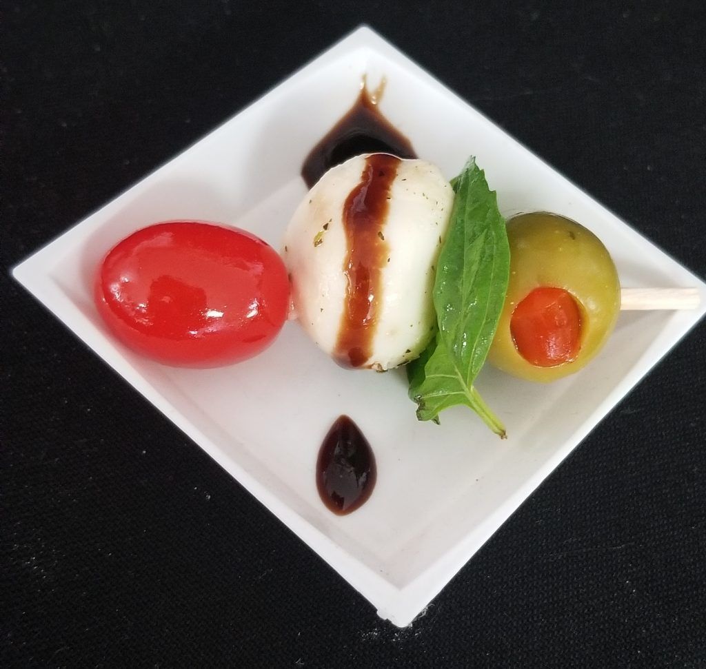 A white plate with a skewer of food on it