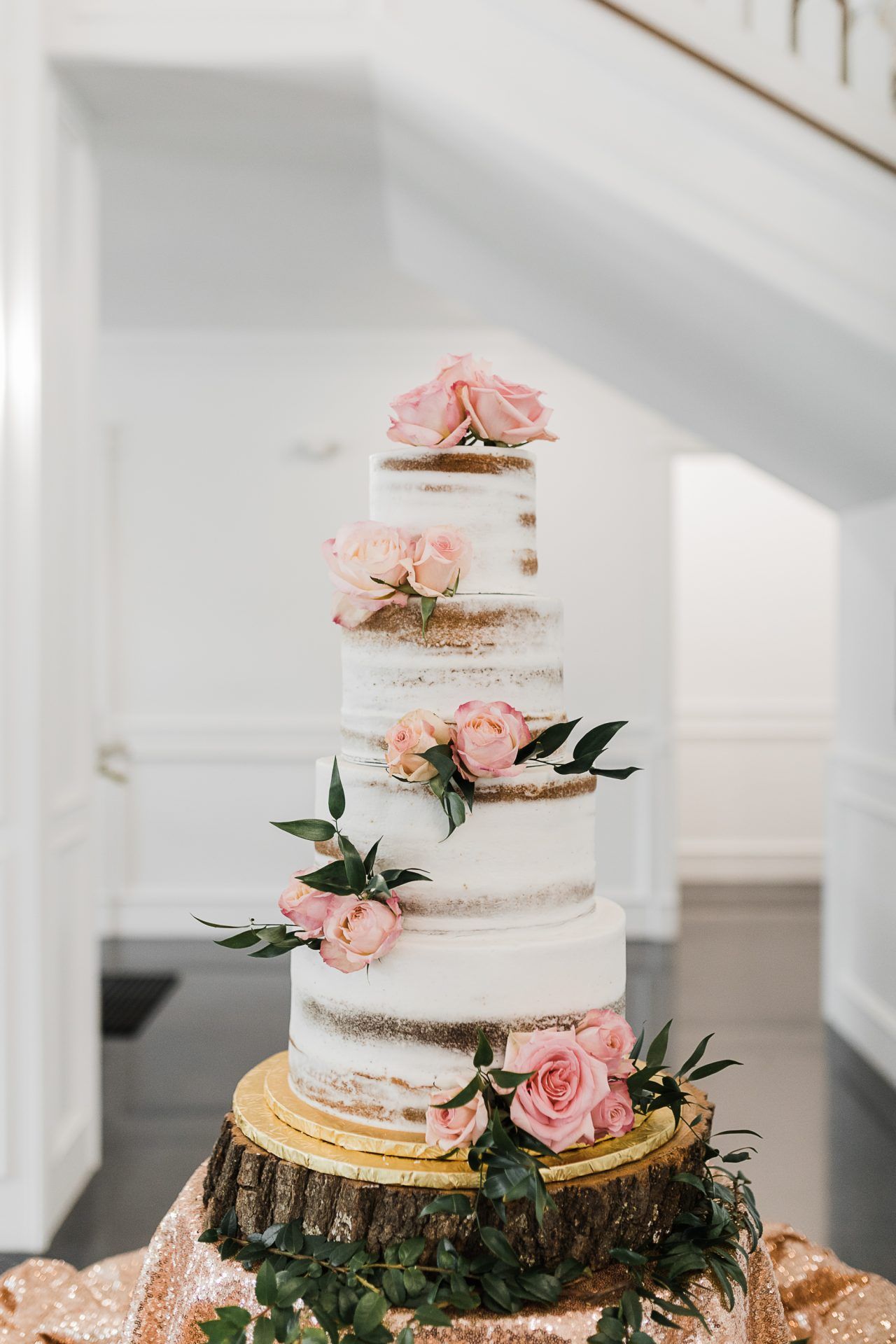 A wedding cake is sitting on top of a wooden stump on a table.