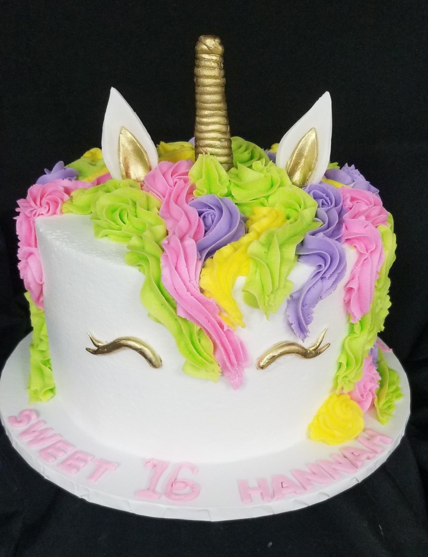 A white cake with a unicorn face on it