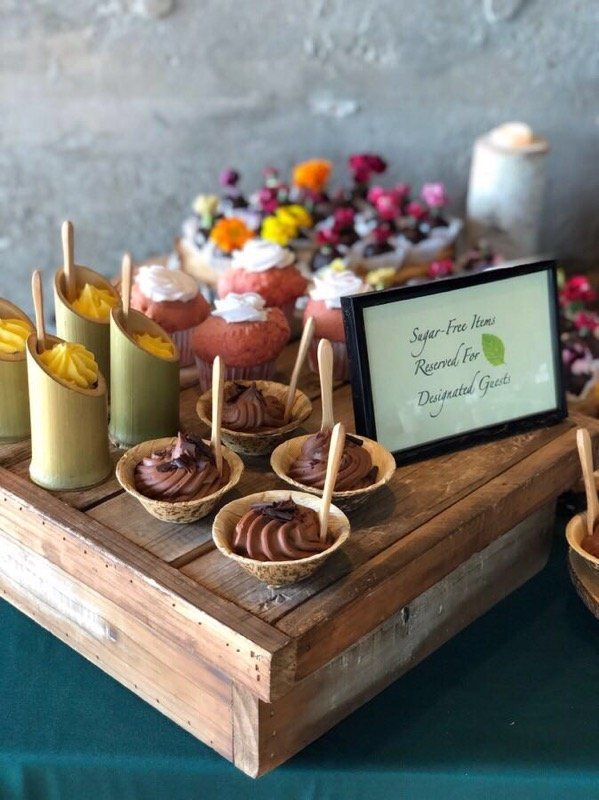 A wooden tray filled with cupcakes and a sign that says tropical spice