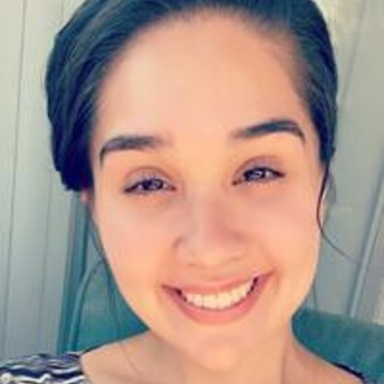 Woman with dark hair, smiling, looking at the camera.