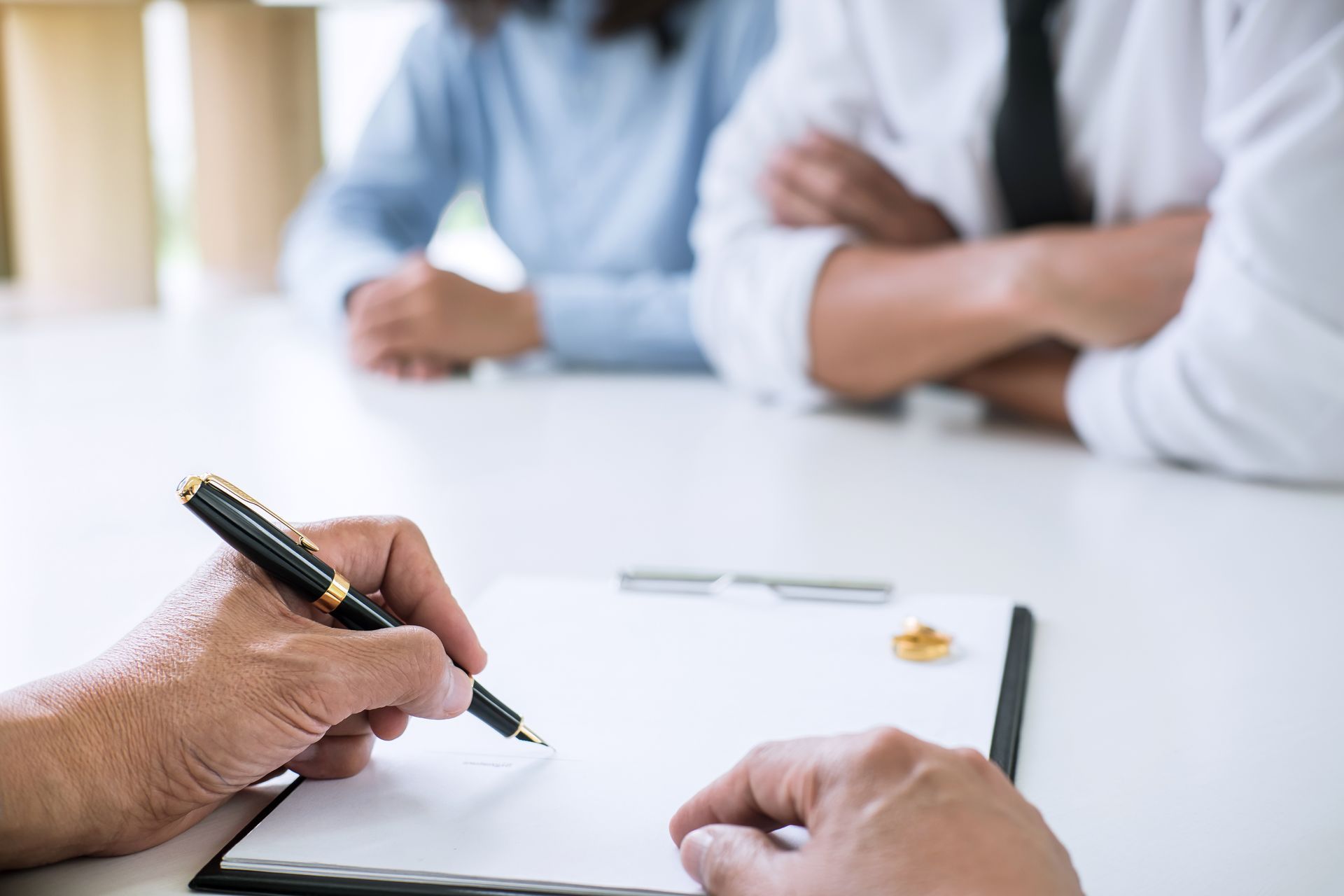 A partial view of a man and woman during a divorce process with a lawyer signing a divorce contract.