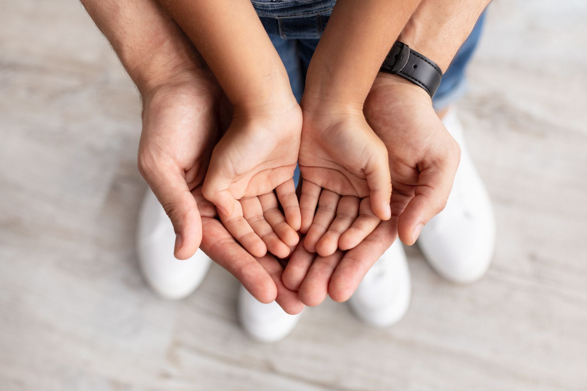 Top view of a man holding a girl's palms in his hands.