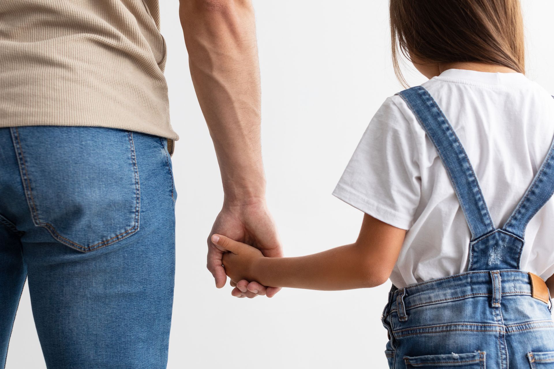 Closeup of father and daughter holding hands.