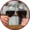 Two hands hold up glasses of red wine for a toast against a blurred indoor background.
