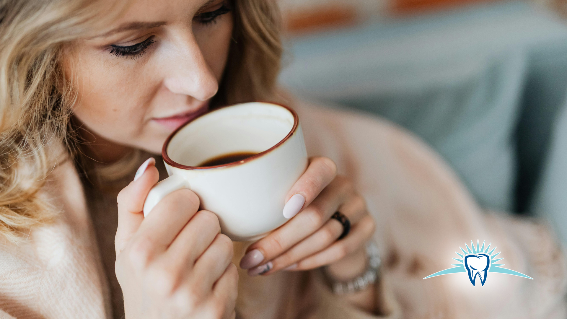 Woman holding and sipping from a white mug, indoors.