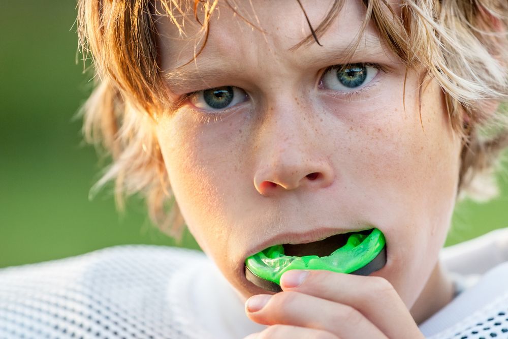A young boy is wearing a green mouth guard.
