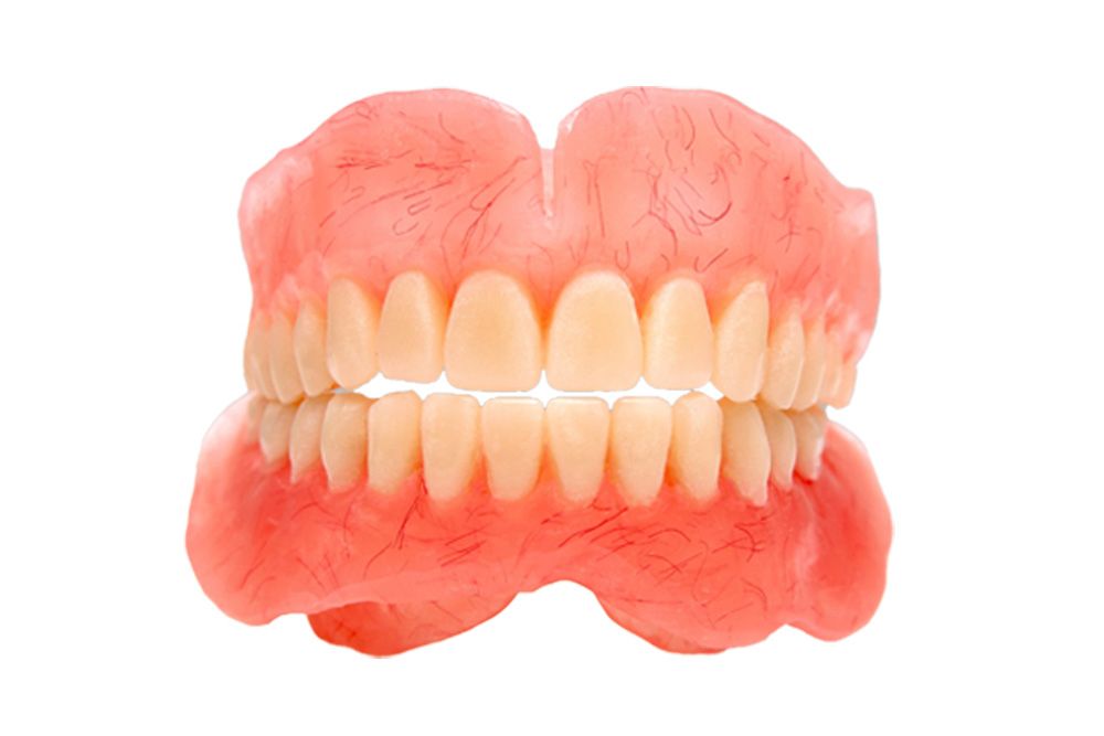 A close up of a denture with white teeth on a white background.