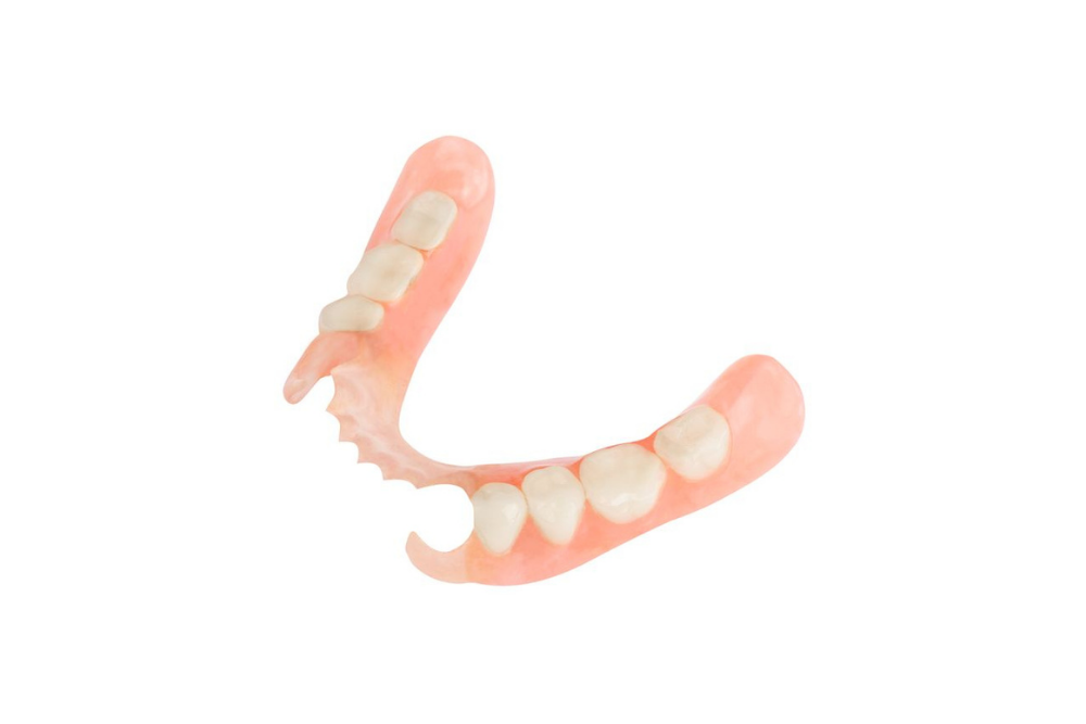 A close up of a denture with teeth on a white background.