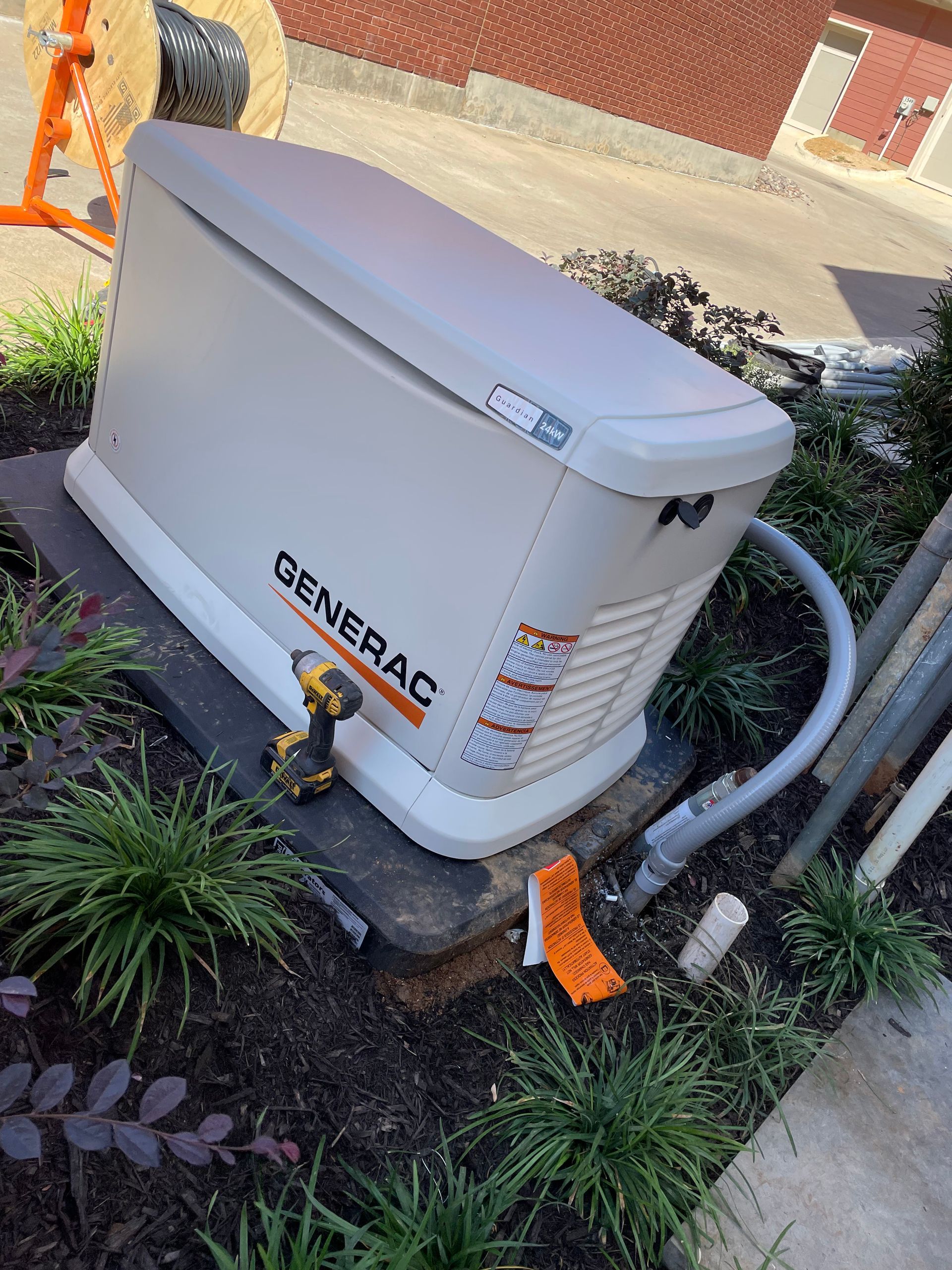 A generator is sitting on top of a concrete block in the grass.