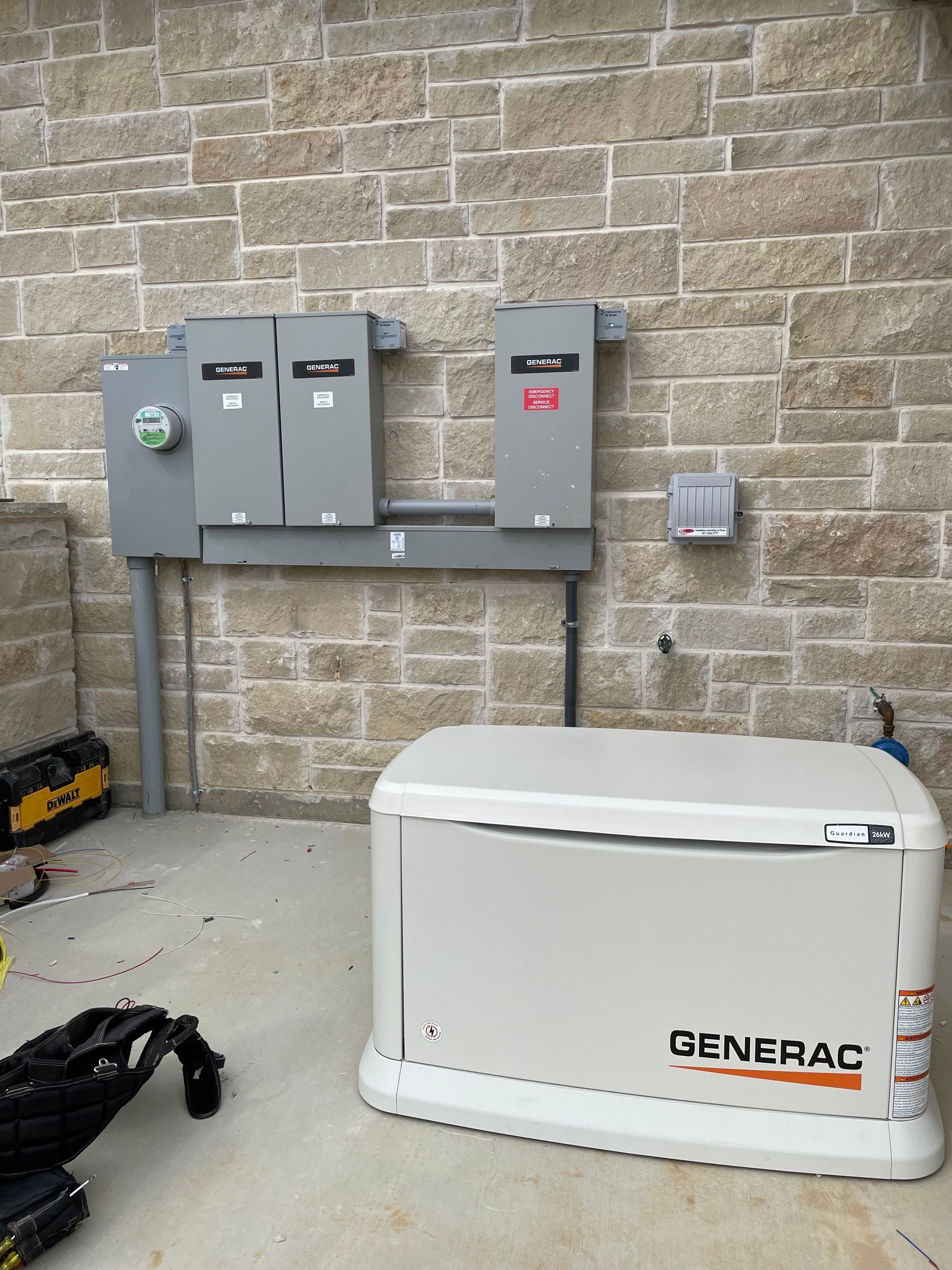 A generator is sitting in front of a brick wall.