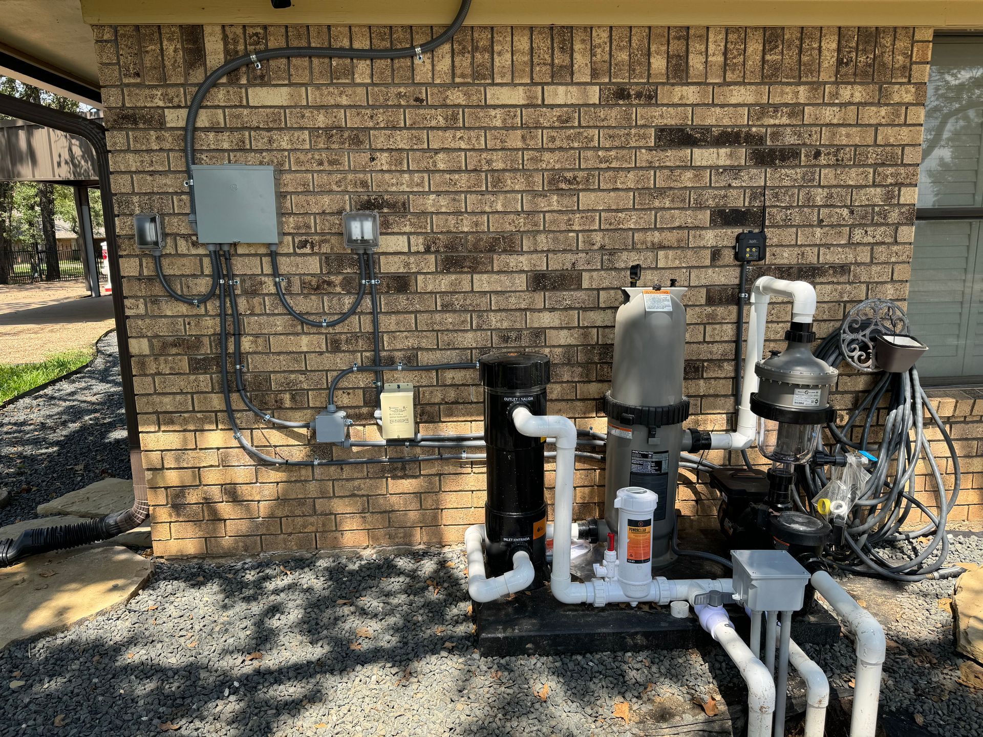 A swimming pool pump is sitting on the side of a brick building.