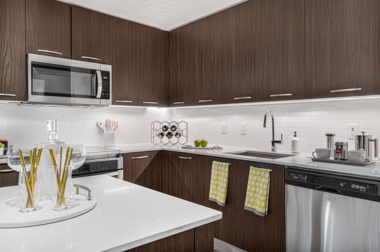Modern kitchen with dark wood cabinets, white countertops, and stainless steel appliances.