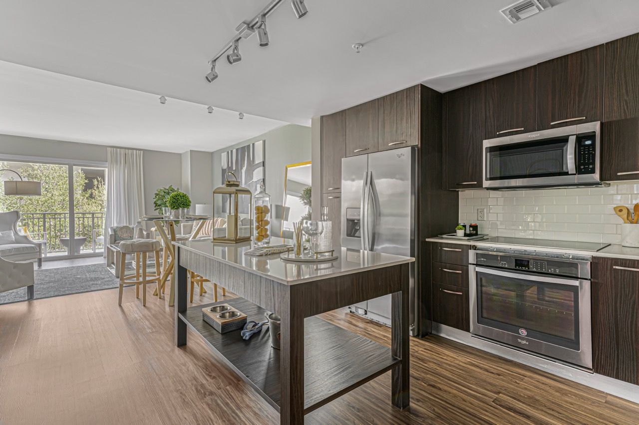 Open-concept kitchen with dark wood cabinets, stainless steel appliances, and an island.