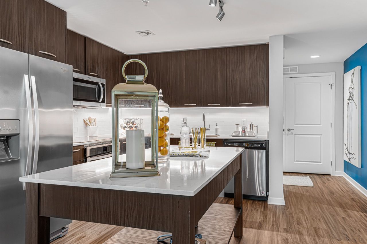 Modern kitchen with dark wood cabinetry, a white island, and stainless steel appliances.