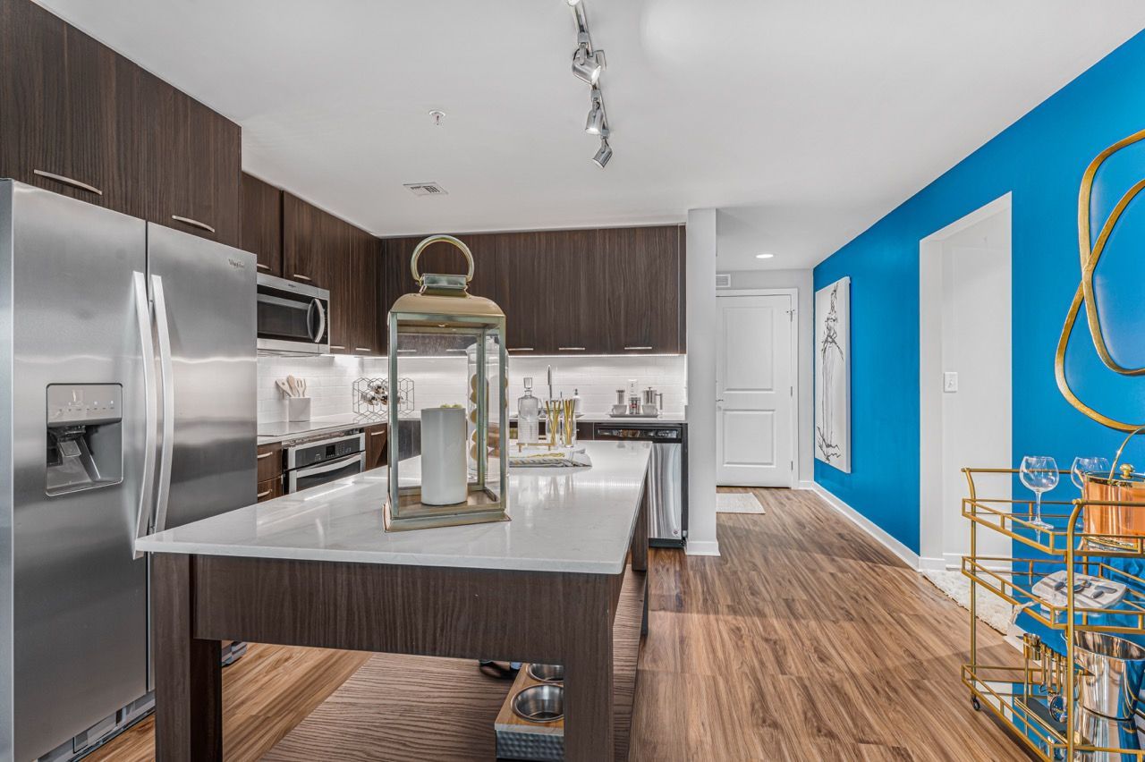 Modern kitchen with dark wood cabinets, stainless steel appliances, and a white island.