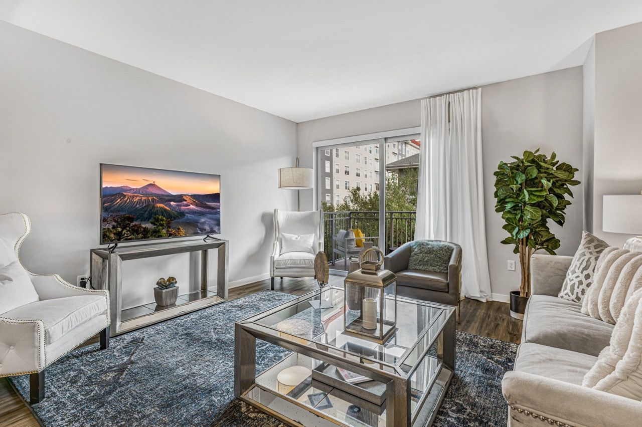 Bright living room in a modern apartment with white seating and a glass coffee table.