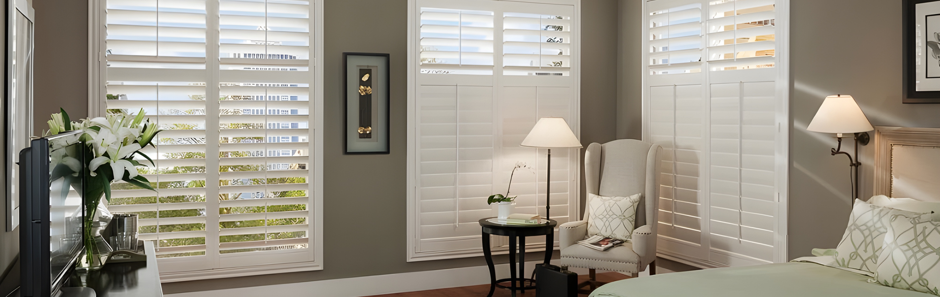 A bedroom with a bed , chair , lamp and shutters on the windows.