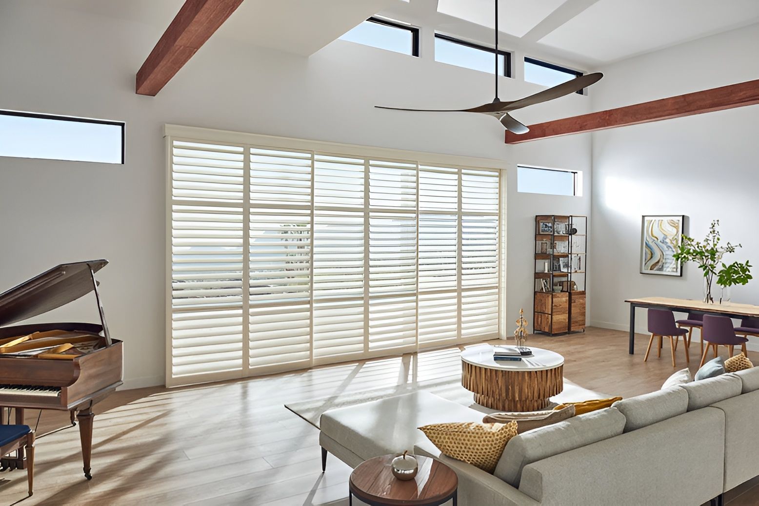 A well-lit living room with a piano and windows, adorned with composite shutter