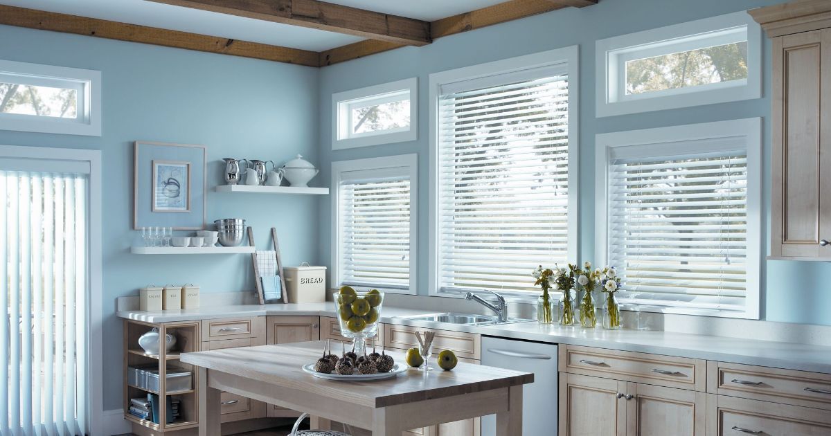 A kitchen with blue walls, wooden cabinets, and faux blinds