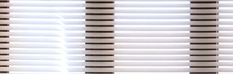 The sun is shining through the blinds of a window.