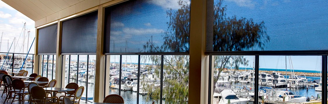 A restaurant with tables and chairs and a view of a marina.