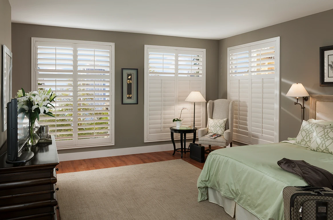Bedroom featuring white composite shutters and a bed.