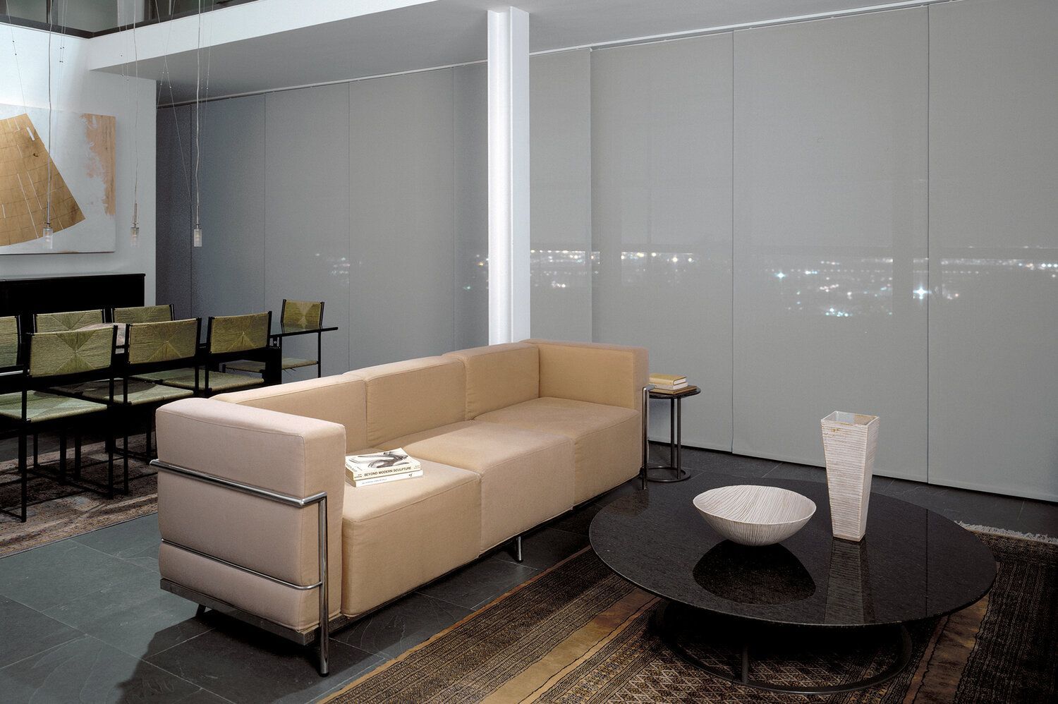 A cozy living room with a couch and a table, featuring sliding panel track blinds.